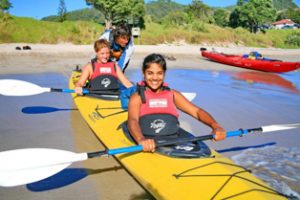 Guides assist double-kayak launch at Hahei Beach, Te Whanganui-A-Hei Marine Reserve