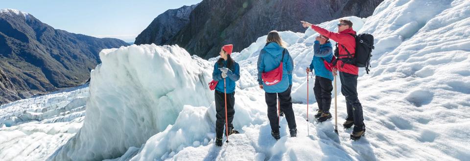 glacier guide at franz josef with tourists pointing out area of interest