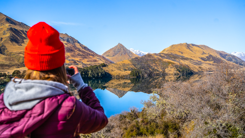 young girl taking picture of Moke Lake, Queenstown