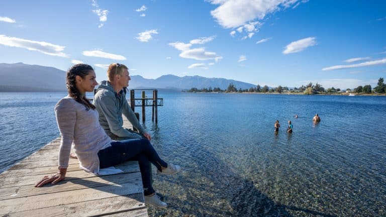 Free-things-to-do-in-te-anau-23 | Must Do New Zealand Yoiung tourist Couple taking int views over the lake from the wharf