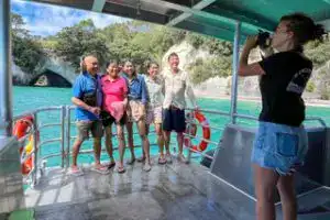 Mercury Bay Discoveries guests posing on boat with Cathedral Cove arch backdrop