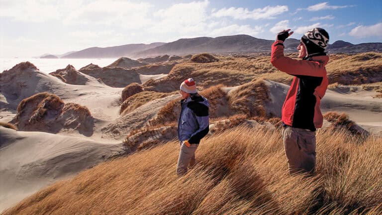 VS Trampers MBay15 | Must Do New Zealand Couple enjoying the scenery on Stewart Island / Rakiura from a coastal lookout