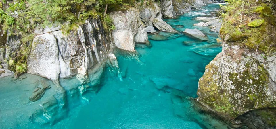 Blue Pools Haast Turquoise river flowing between mossy rock cliffs in a narrow canyon with trees above