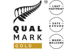 Qualmark Gold logo with fern symbol and three circular badges: Light Footprint, Safe & Sound, Warm Welcome.